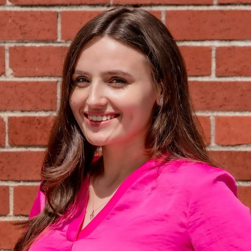 2_101554_15968869 A woman in pink shirt standing next to brick wall.