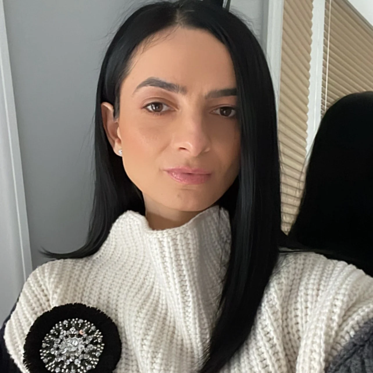 2_101554_21992487 A woman in white sweater holding a black and white button.